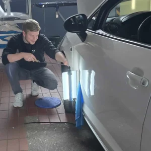 Fachgerechtes lackierfreies Ausbeulen an einem weißen Fahrzeug – präzise Dellenentfernung ohne Lackschaden bei der Lackiererei in Schmallenberg.